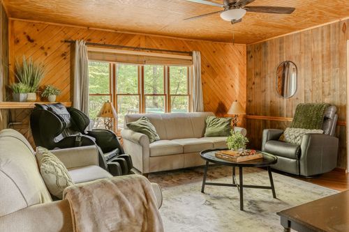 Living room with wood paneling, a massage chair, cream sofa and round coffee table.