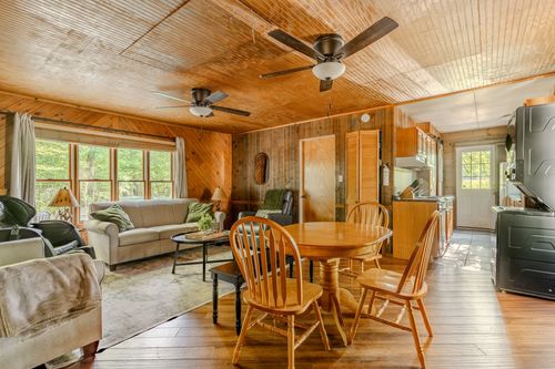 Open living and dining area with wood ceilings, two ceiling fans and a round dining table.