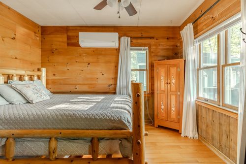 Bedroom with a log-style bed frame, wood ceiling fan and a small painted armoire.