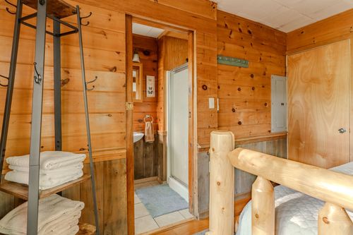 Hallway nook with a ladder towel rack, leading to an ensuite bathroom and log bed frame.