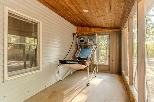 Screened porch with an arcade-style basketball hoop game and wood-plank ceiling.