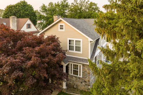 Aerial view of a two-story craftsman home with stone accents, framed by colorful fall foliage.