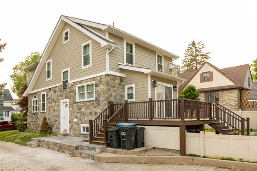 Side view of a stone-and-siding home with new multi-level wood deck and staircase