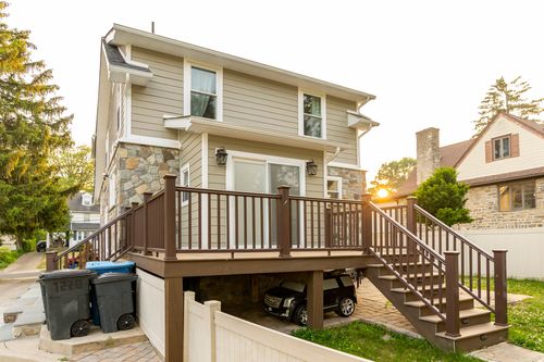 Backyard view of a new wood deck with railings at golden hour, cars parked underneath