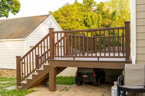 Elevated wood deck with staircase down to a driveway parking space beneath it