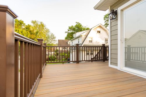 Empty wood deck with dark railings and a view of a neighboring gambrel-roofed house