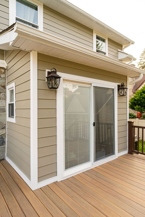 Sunroom addition corner with sliding glass door, lantern sconces and new wood deck