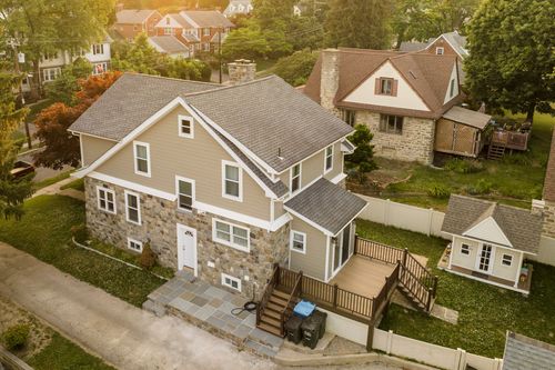 Aerial view of a stone-accented craftsman home with a new rear deck and street-side curb appeal.