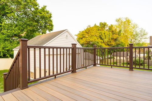 Wood deck railing overlooking a detached white garage and green backyard