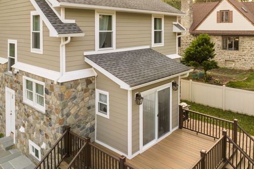 Aerial close-up of a new sunroom addition with sliding glass doors above a wood deck