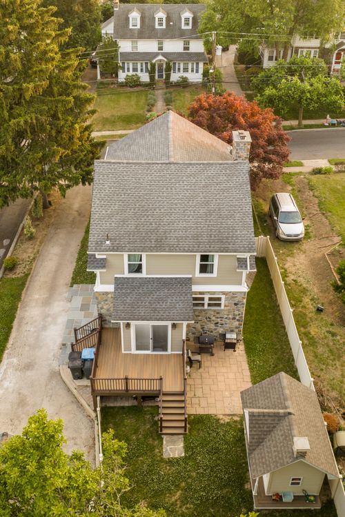 Aerial top-down view of a home with new deck addition, patio and stone foundation