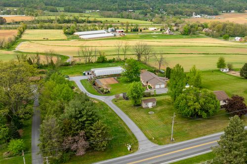Aerial view of a rural property with ranch home and greenhouse nursery surrounded by farmland