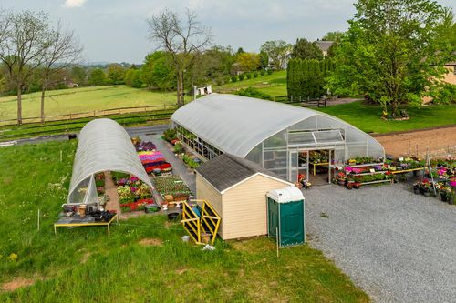 Aerial view of twin hoop-house greenhouses filled with nursery plants and garden beds