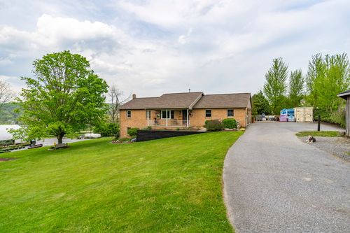 Brick ranch home with covered porch overlooking a lake and distant rolling hills