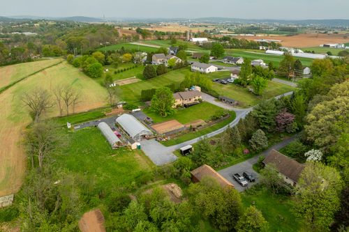 Aerial view of a rural property with home, greenhouse and garden plots amid farmland