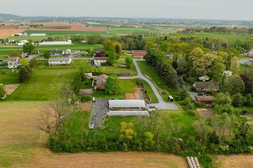 Aerial view of a brick home with greenhouse nursery operation set among green hills