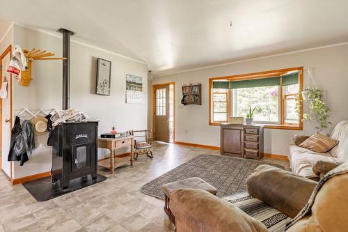 Living room with wood stove, vaulted ceiling and bay window with a cozy reading nook