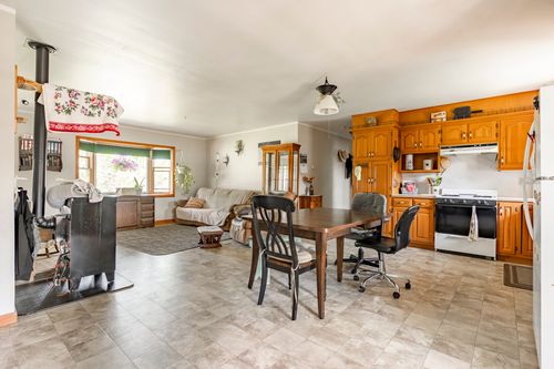 Open dining and kitchen area with wood stove, oak cabinetry and table set for four