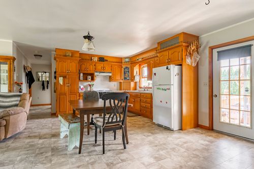 Kitchen with oak cabinetry, dining table and bench seating beside a door to the deck
