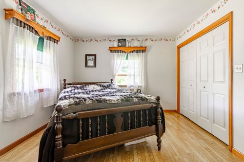 Bedroom with a dark wood four-poster bed and floral wallpaper border trim