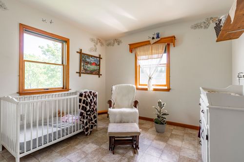 Nursery with a white crib, upholstered rocking chair and matching ottoman