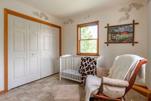 Nursery with a white crib beside white closet doors and framed farmhouse artwork