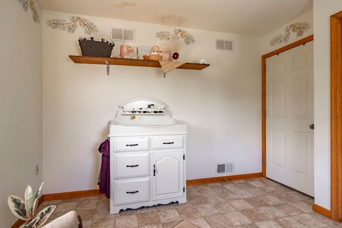 Nursery corner with a white changing table dresser and a shelf holding baskets