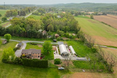 Aerial view of a nursery greenhouse with garden beds set against a wooded hillside