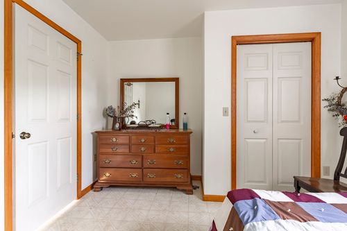 Bedroom corner with a wood dresser and mirror flanked by closet doors on both sides