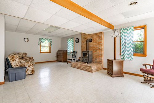 Finished basement rec room with brick wood-stove surround, chevron curtains and cozy seating