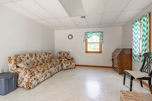 Finished basement room with a floral sofa, chevron curtains and a wood secretary desk