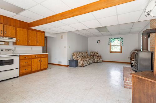 Basement kitchenette with wood cabinets and a floral loveseat beneath an open ceiling beam