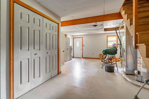 Basement hallway with closet doors and an open wood staircase leading upstairs