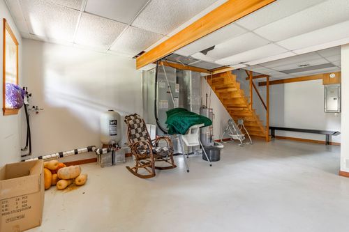Basement storage area with a rocking chair, exercise equipment and open wood staircase