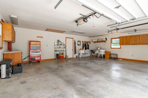 Basement workshop area with a rolling tool chest, wire shelving and a utility sink