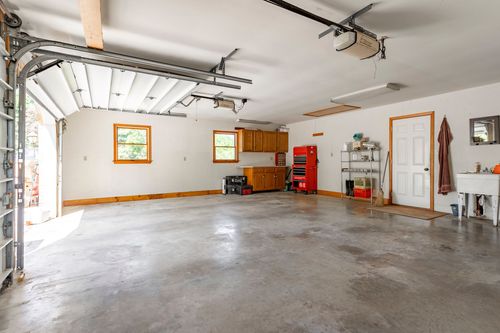 Two-car garage interior with an open bay door, tool chest and built-in wood cabinetry