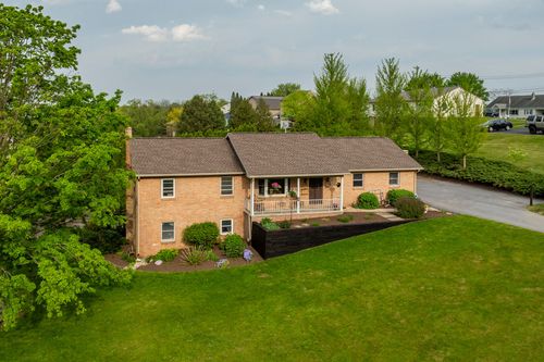 Brick ranch home with covered front porch and hanging flower baskets on a green lawn