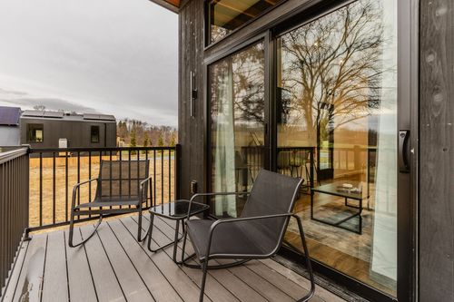 Covered deck with modern outdoor seating and a glass sliding door reflecting the sunset