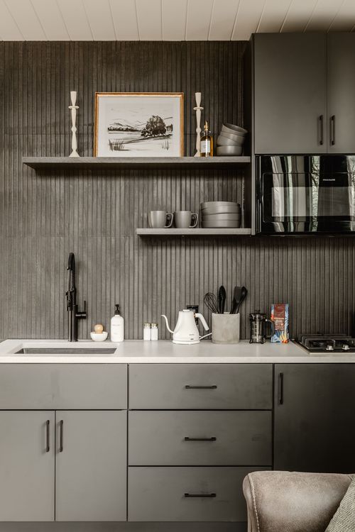 Charcoal ribbed backsplash kitchenette with open shelving, gas cooktop and black hardware