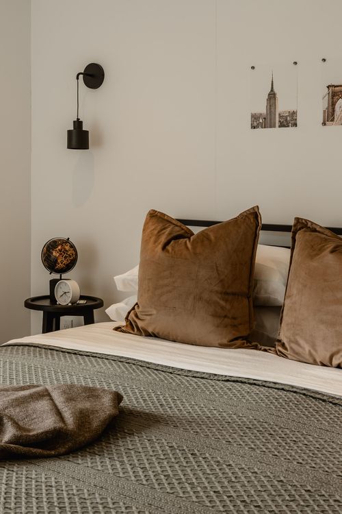 Bedside styling with globe, alarm clock, black pendant sconce and velvet throw pillows