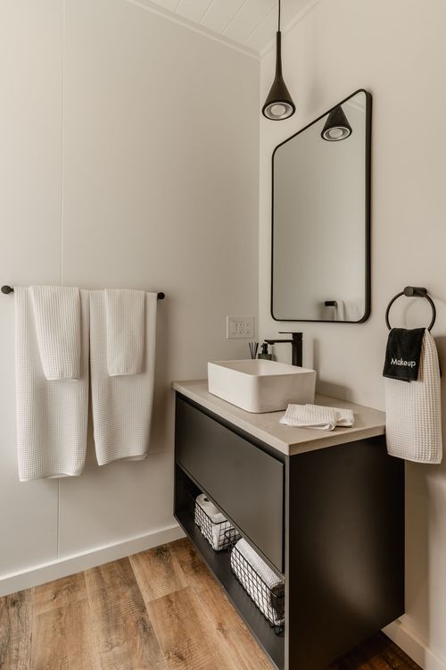 Bathroom vanity with an arched black-framed mirror, pendant light and white vessel sink