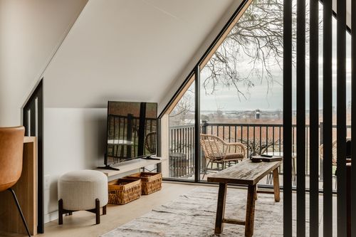 A-frame loft with a black vertical slat partition, cream ottoman and reclaimed wood bench