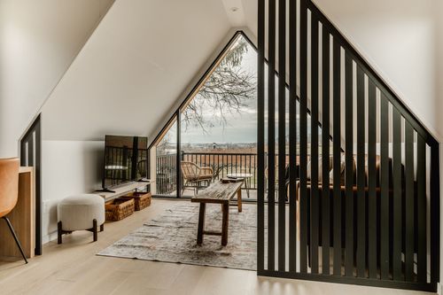 Loft seating area framed by a black slat room divider, layered rug and rustic bench