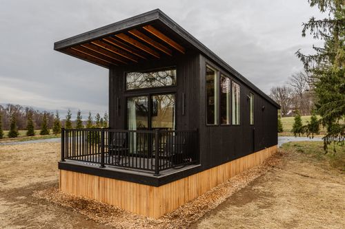 Four black Adirondack chairs around a fire pit overlooking rolling countryside