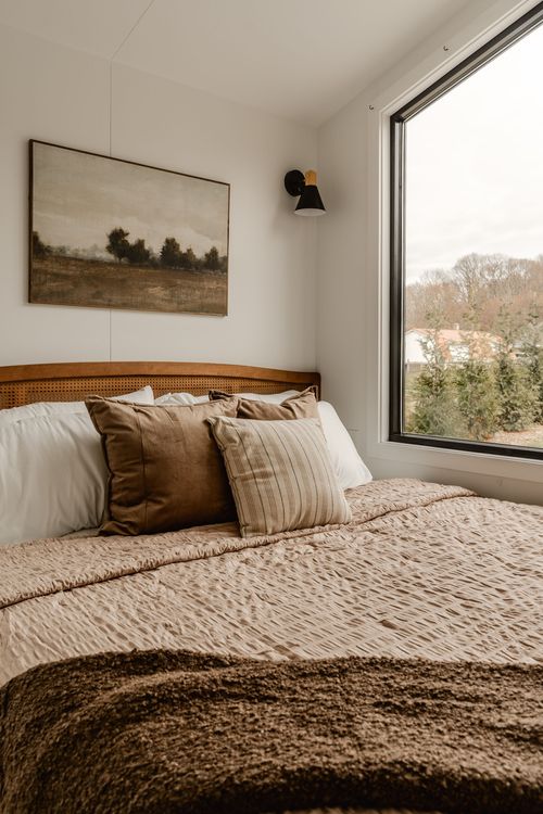 Bedroom corner with landscape art, wall sconce and a window overlooking distant rooftops
