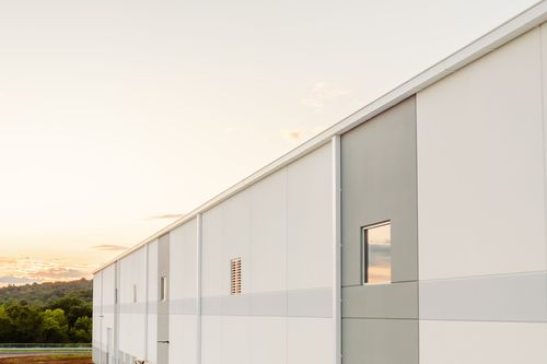 Loading dock doors and dock leveler bumpers along a two-tone warehouse exterior