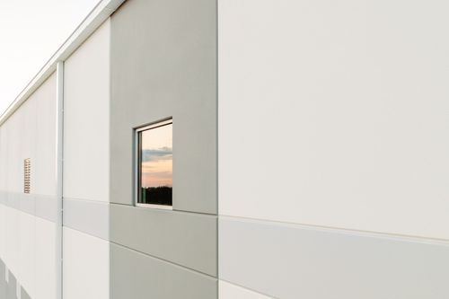 Close-up of angled metal wall panels meeting at a corner seam in white and gray tones