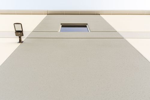 Wall-mounted light fixture beside a small square window on a gray and cream panel