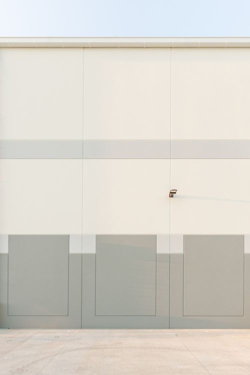 Cream metal wall with a gray horizontal stripe and a wall-mounted light fixture