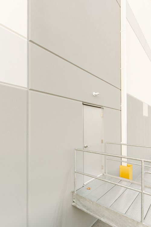 Metal stairway with a yellow safety marker leading to a gray access door